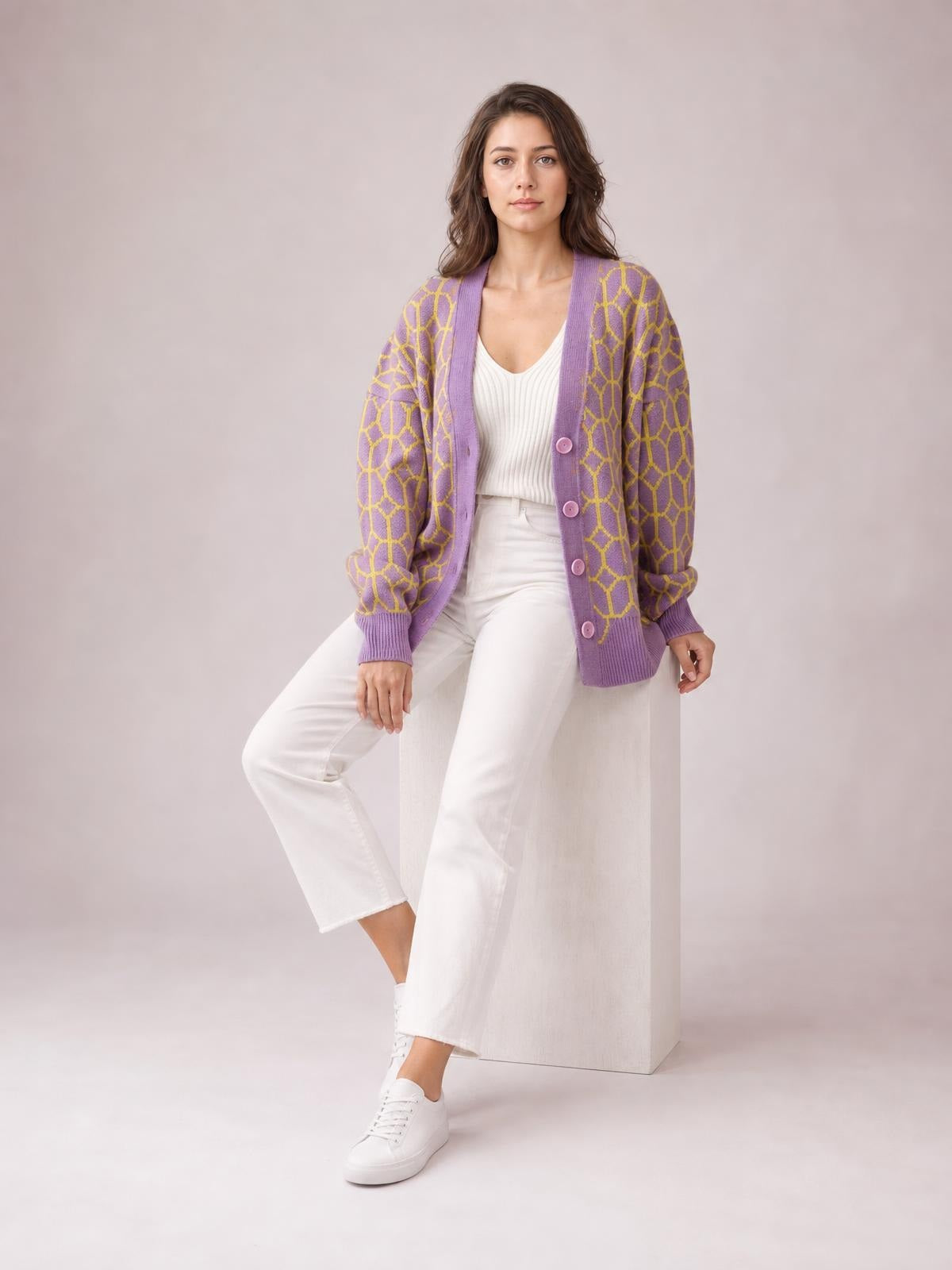 A model poses in a purple button-up long sleeve cardigan with a yellow geometric pattern, ribbed cuffs and hem, and a relaxed silhouette.