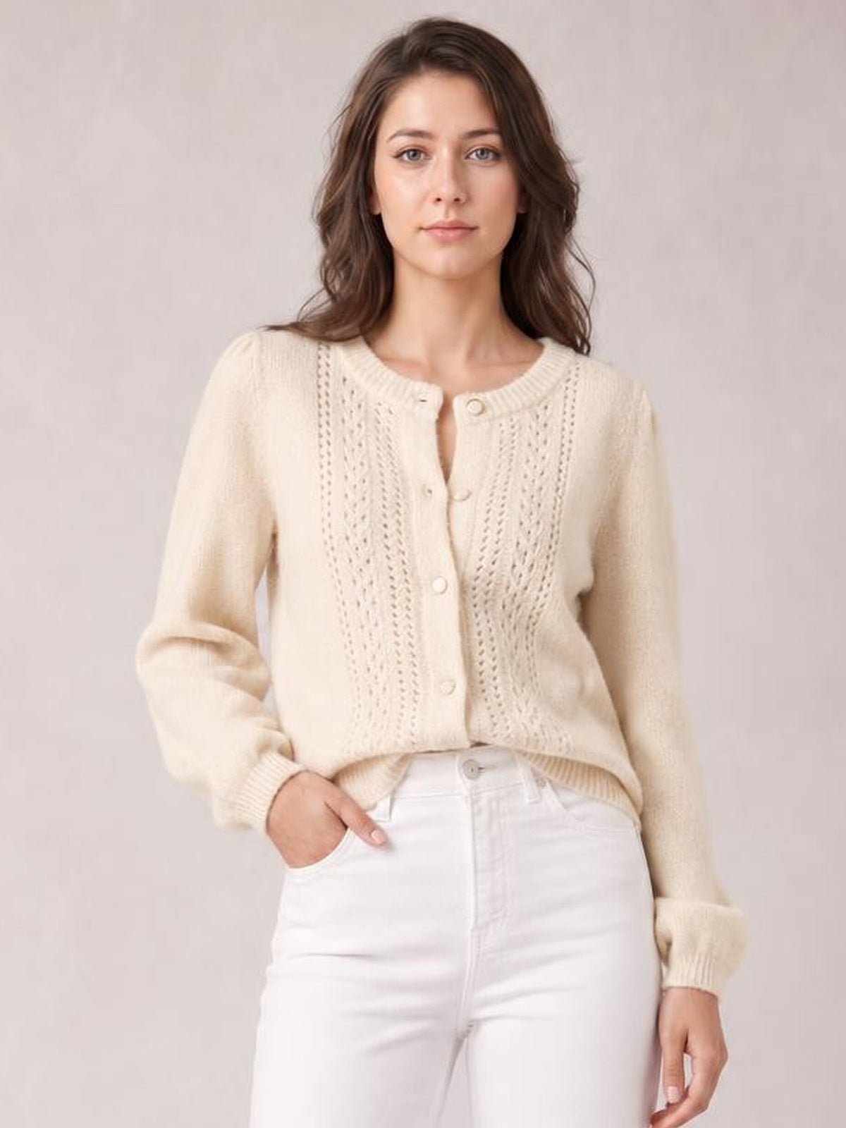 Model wearing a cream button-up long sleeve cardigan with a round neckline, textured knit front panels, ribbed cuffs, and a relaxed waist-length silhouette.