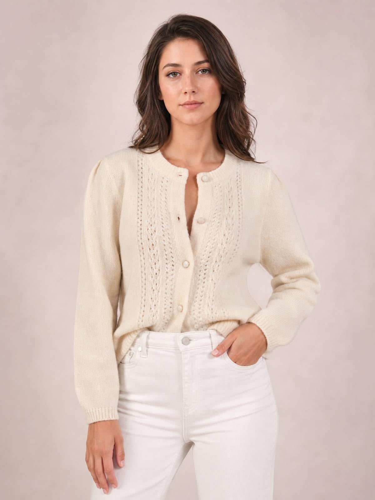 A model wears an ivory button-up long sleeve cardigan with a round neckline, textured open-knit front panels, ribbed cuffs, and a relaxed silhouette.