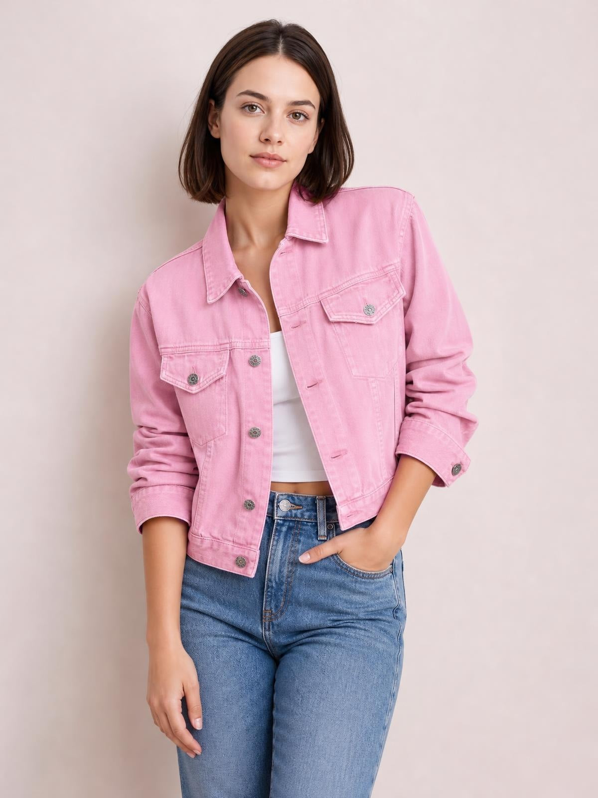 A model wears a pink button-up long sleeve denim jacket with a pointed collar, flap chest pockets, metal buttons, and a relaxed waist-length silhouette.