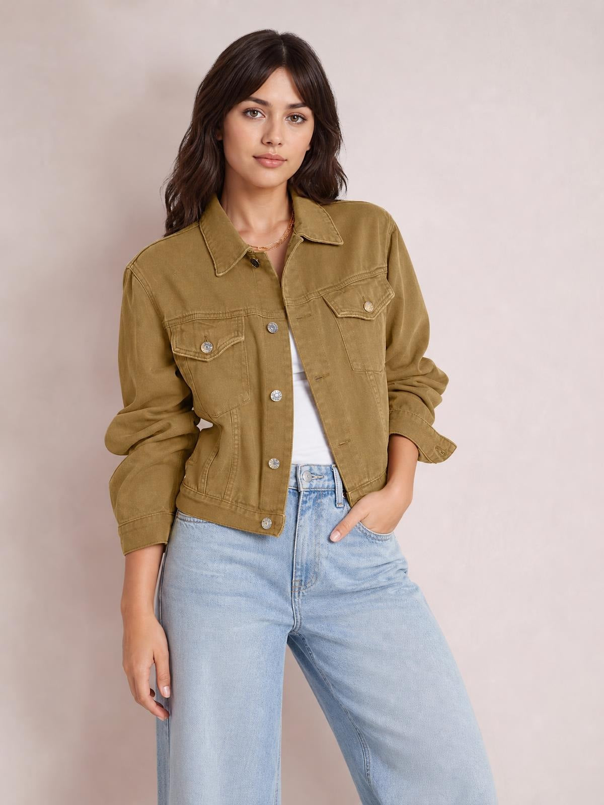 A model wears an olive-brown button-up long sleeve denim jacket with a pointed collar, flap chest pockets, relaxed silhouette, and rolled cuffs.
