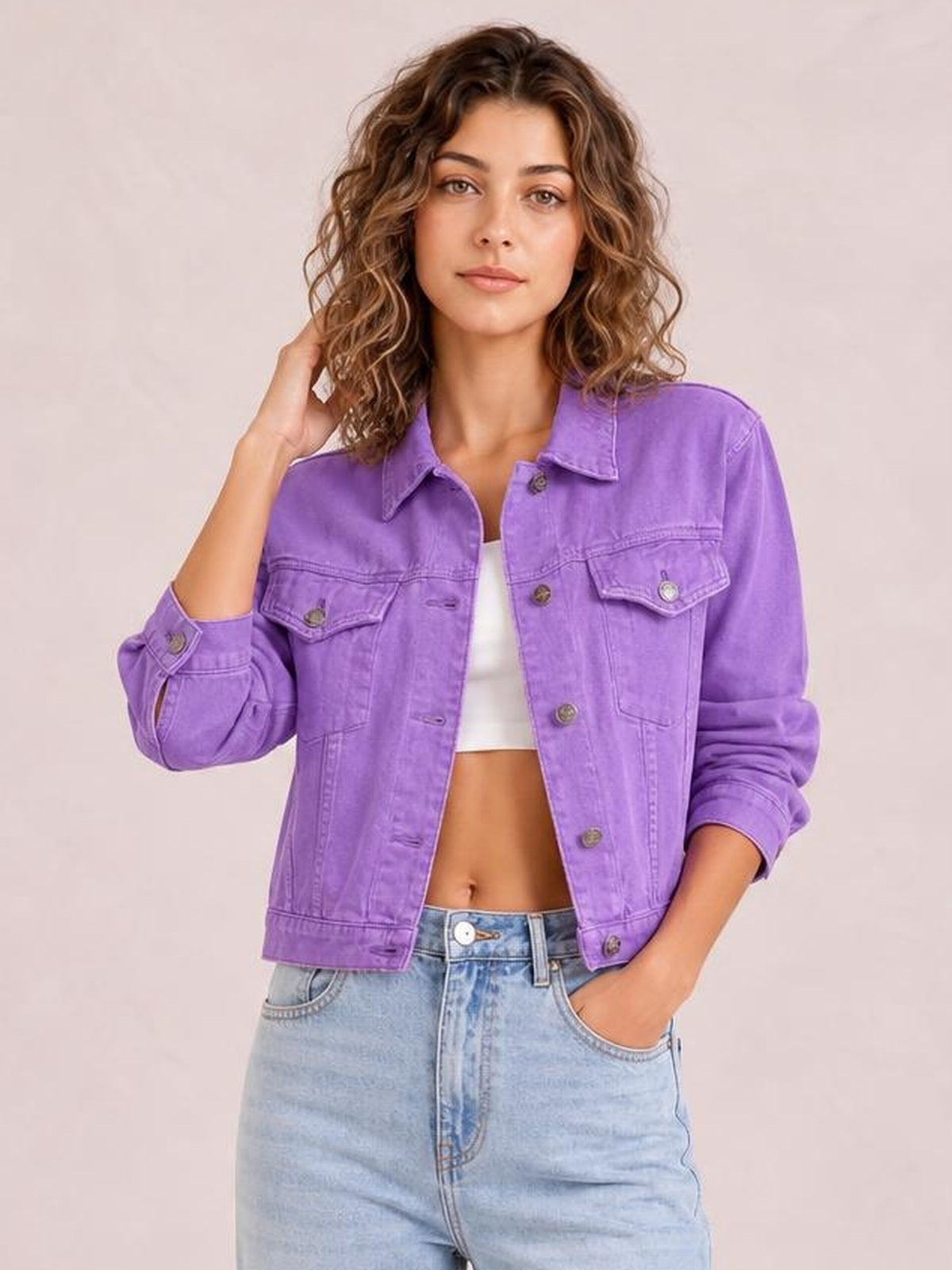 Model poses in a purple button-up long sleeve denim jacket with a collared cropped silhouette, chest flap pockets, cuffed sleeves, and front buttons.