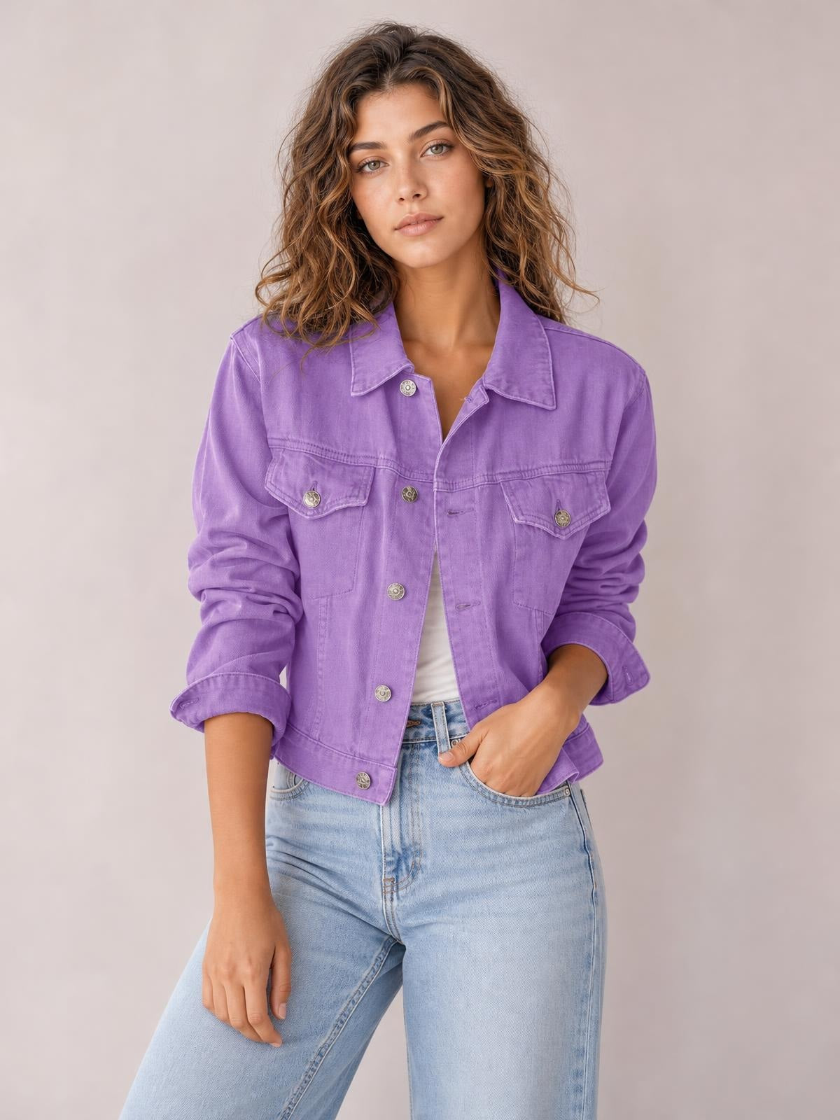Model poses in a purple button-up long sleeve denim jacket with a collared neckline, flap chest pockets, rolled cuffs, and a waist-length silhouette.