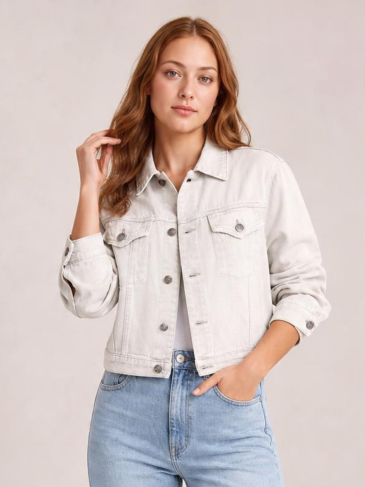 Model wearing a light-wash button-up long sleeve denim jacket with a collared, relaxed silhouette, flap chest pockets, front buttons, and rolled cuffs.