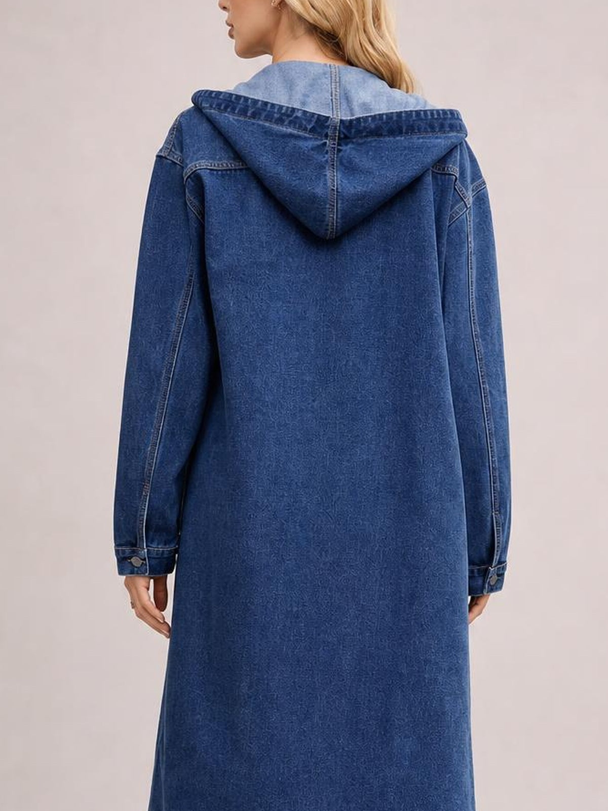 Model shown from behind wearing a blue longline hooded denim outerwear shirt with long sleeves, seam detailing, button cuffs, and a relaxed silhouette.