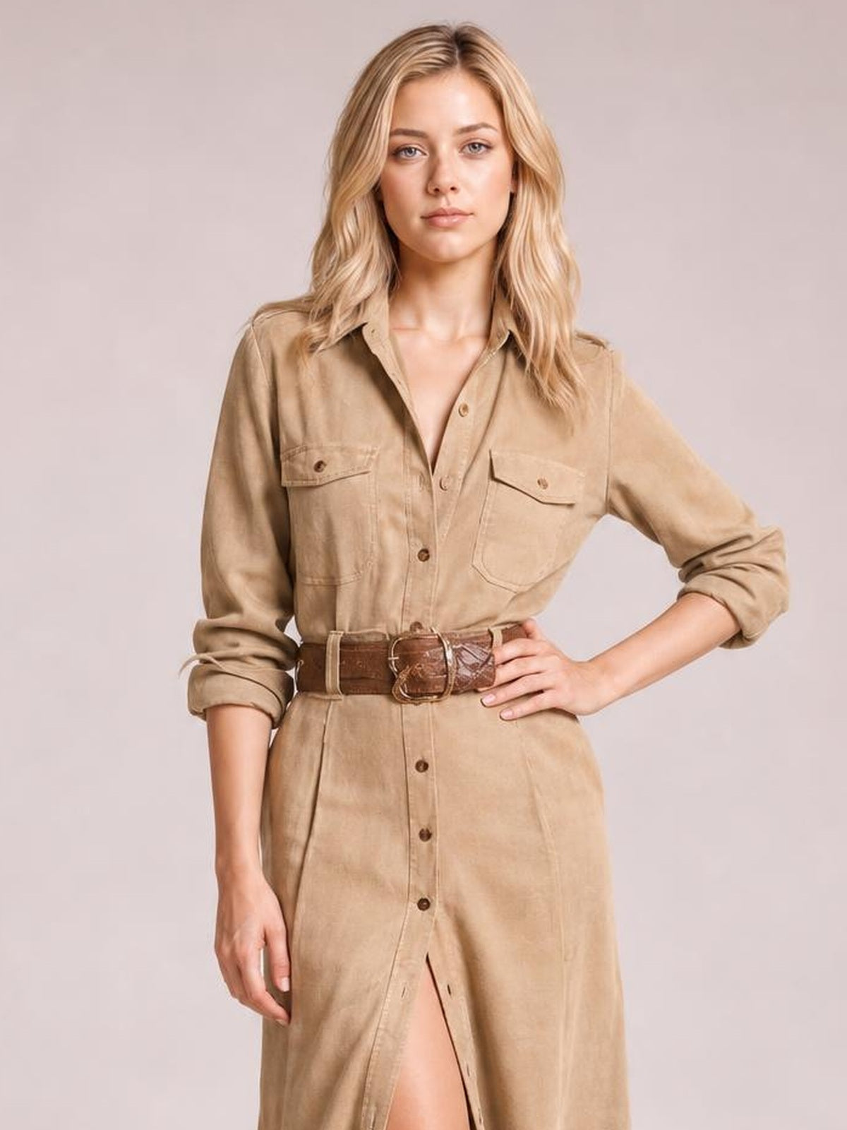 Model wears a tan button-up long sleeve shirt dress with chest pockets, rolled cuffs, a belted waist, and a straight midi silhouette with front slit.