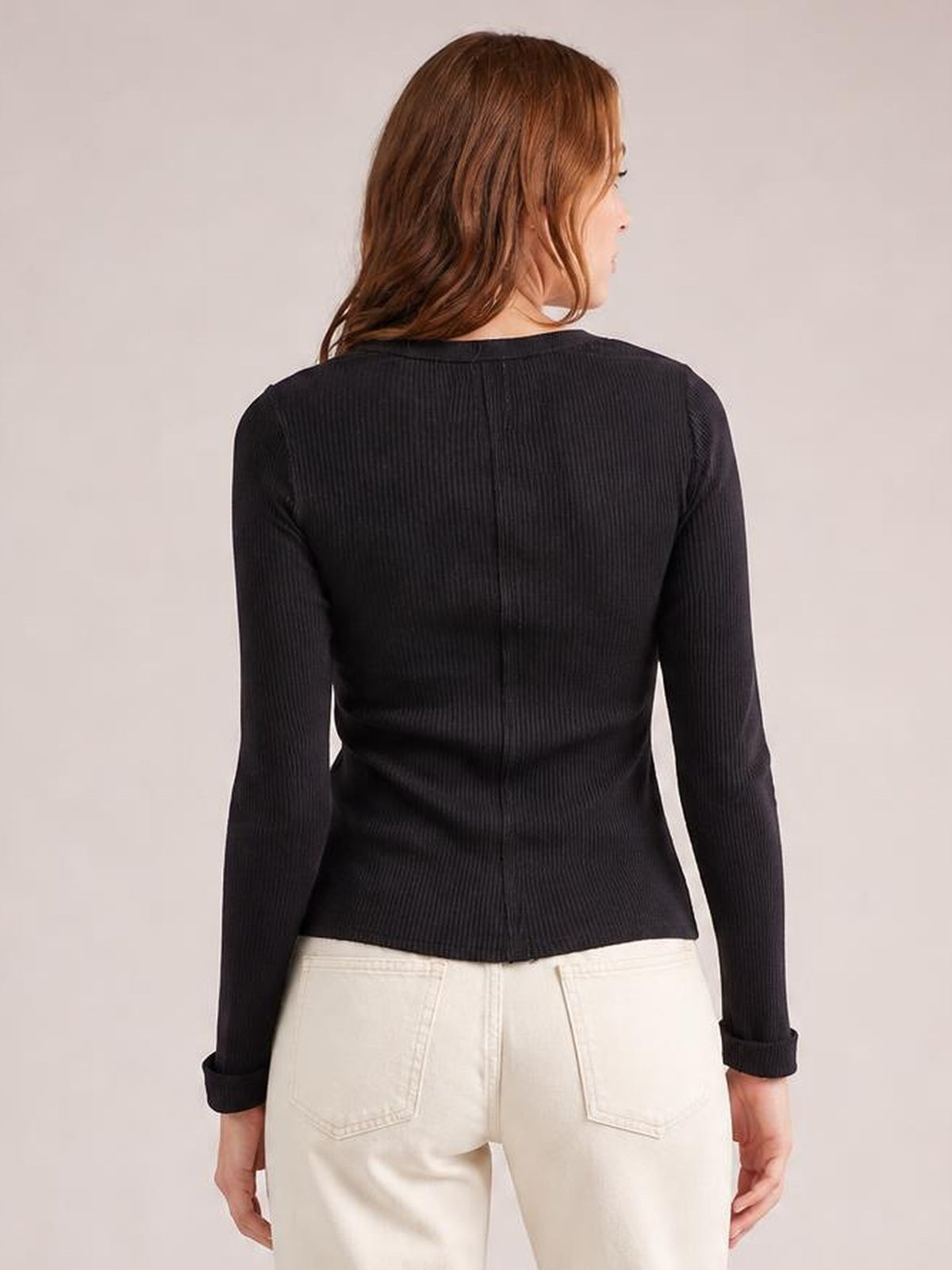 Model shown from the back wearing a black round-neck long-sleeve cardigan with a fitted silhouette, vertical ribbed texture, buttoned front, and cuffed sleeves.