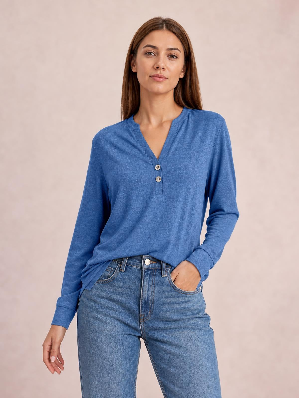 Model wearing a relaxed blue long sleeve top with a notched neckline, two-button placket, and slightly loose silhouette, paired with jeans.