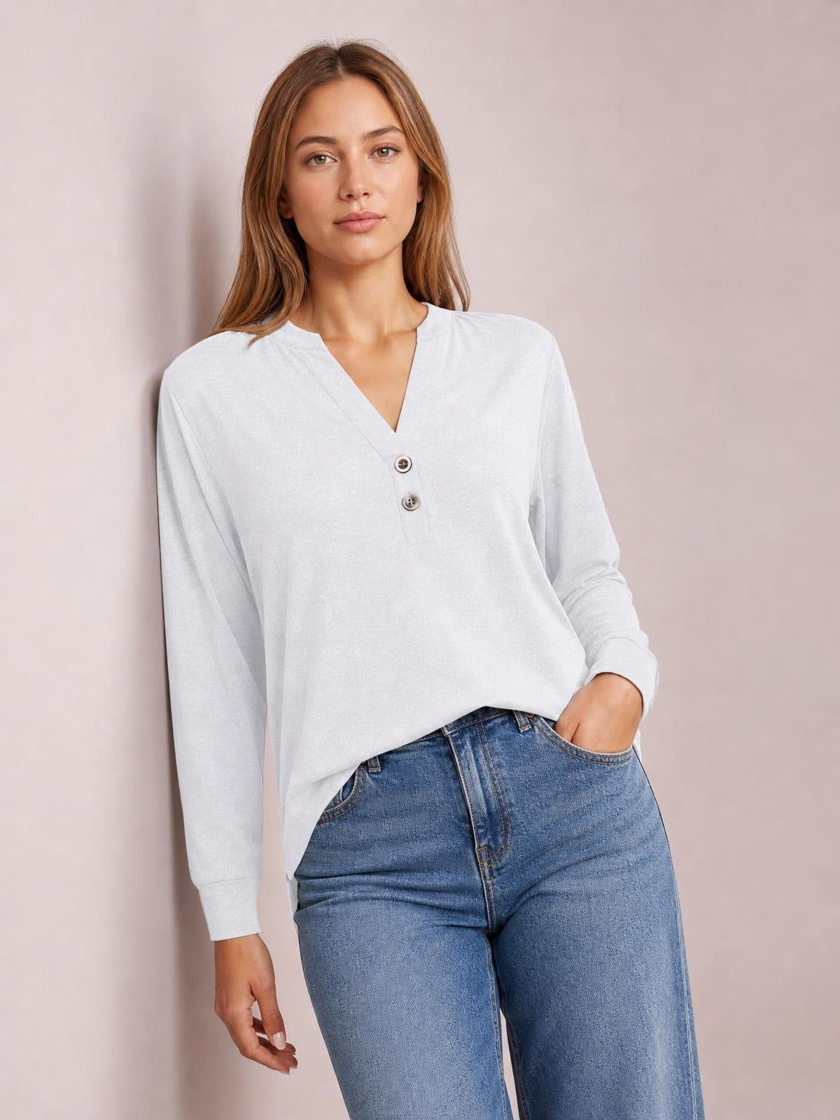 Model wearing a light gray buttoned notched-neck long-sleeve top with a relaxed silhouette, ribbed cuffs, and two visible front buttons, paired with jeans.