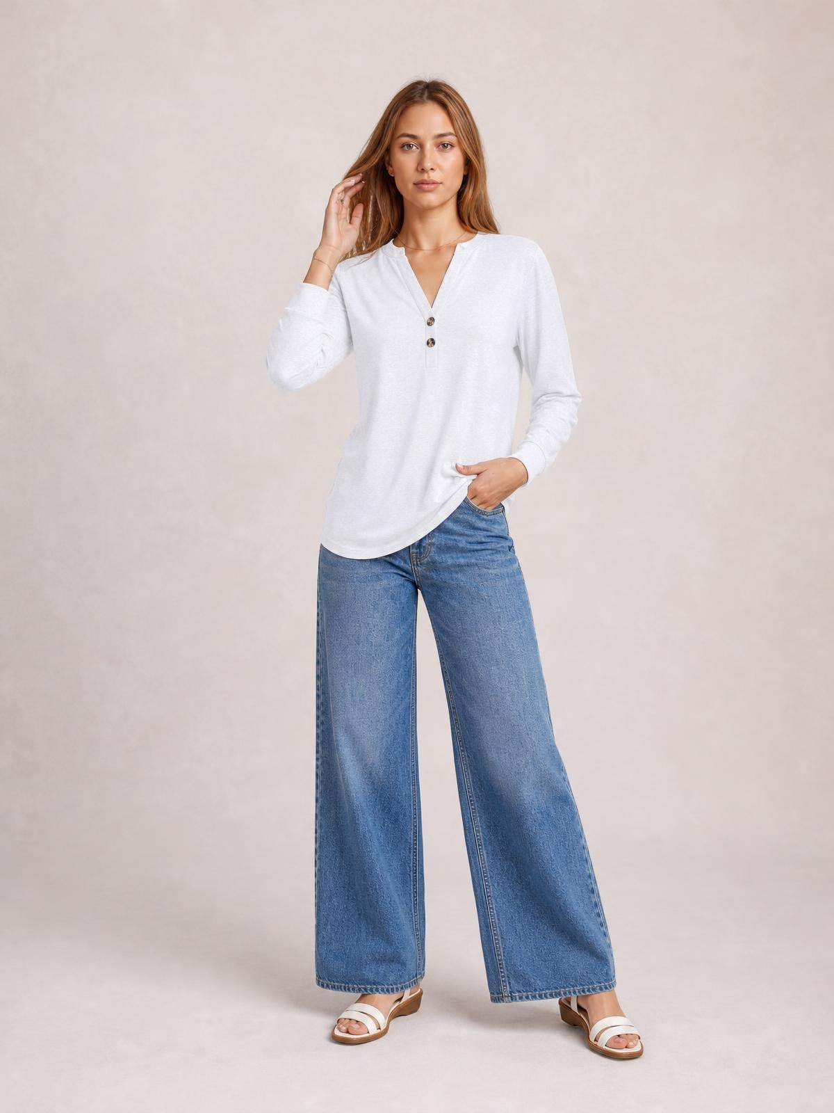 Model wearing a white buttoned notched neck long sleeve top with a relaxed silhouette, posing with one hand in her jeans pocket.