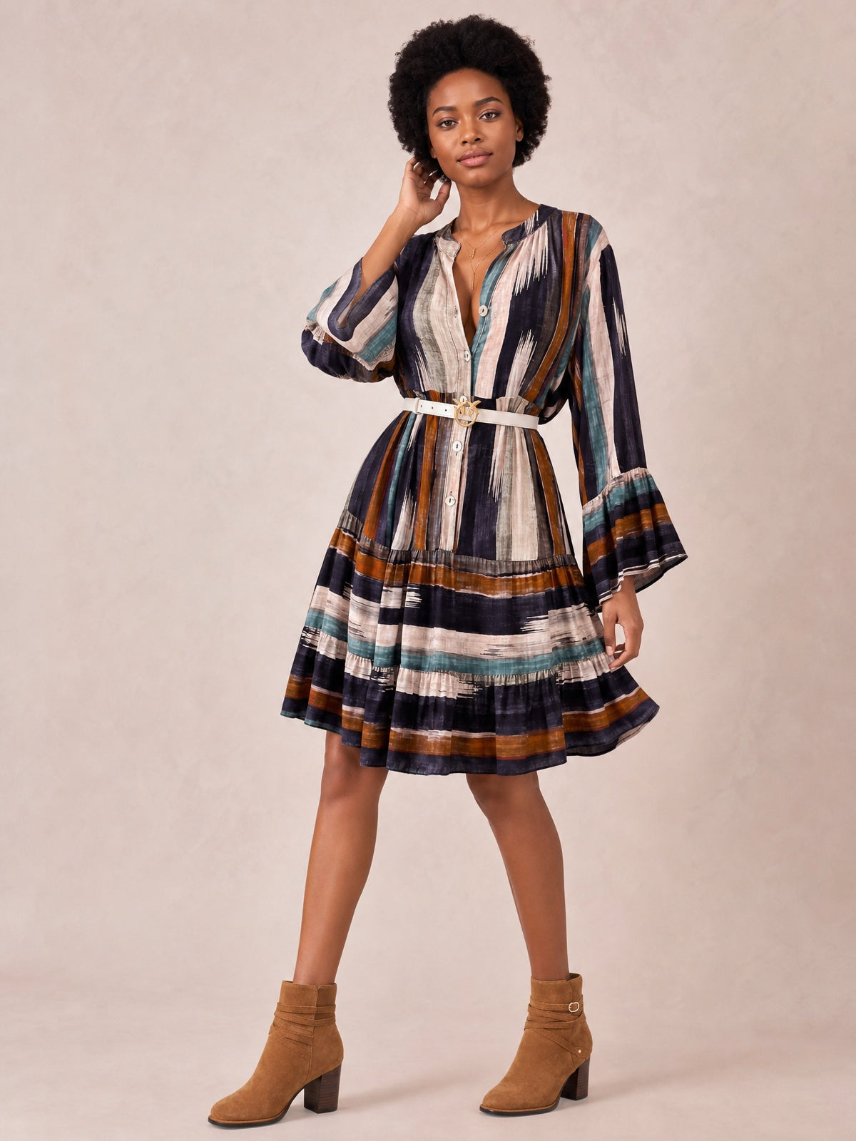 A model poses in a multicolored striped mini dress with long bell sleeves, a button front, belted waist, and softly flared tiered skirt.