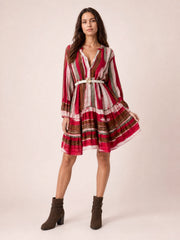 Model wearing a red, brown, and gray striped button-front long-sleeve mini dress with a belted waist and softly flared skirt, holding the hem to show its movement.