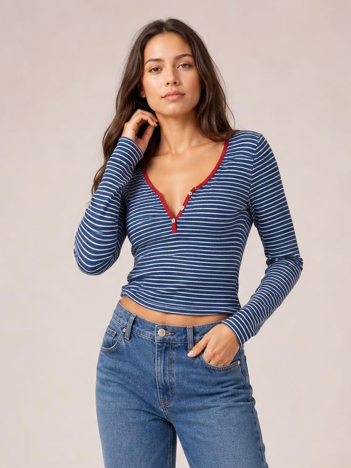 Model wears a navy and white striped long sleeve T-shirt with a buttoned red-trimmed neckline and fitted cropped silhouette.