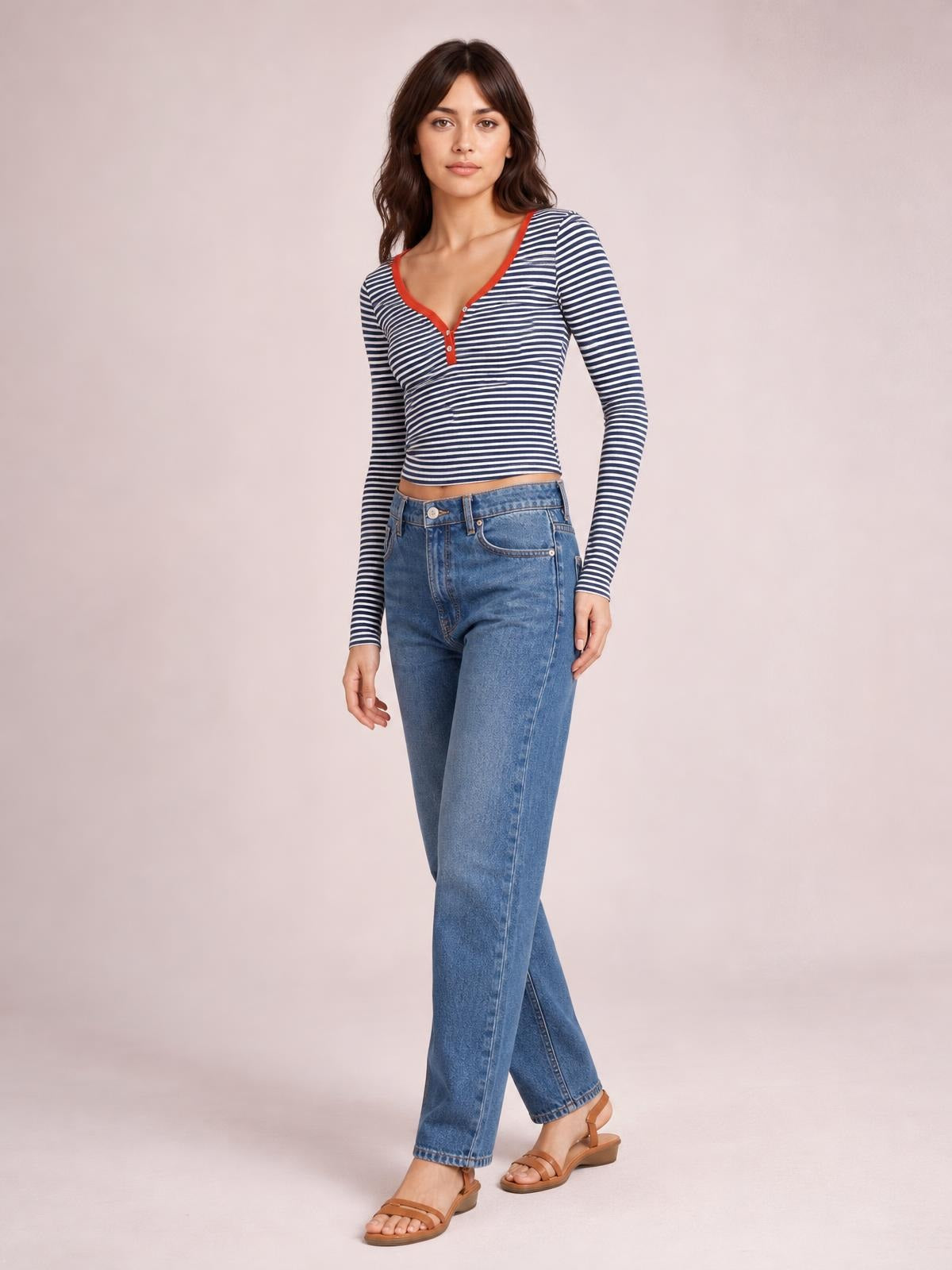Model poses in a fitted navy-and-white striped long sleeve T-shirt with red-trimmed neckline, button placket, and cropped silhouette.