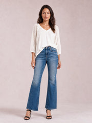 Model wears blue bytos high-rise bootcut jeans with front pockets, distressed details, a fitted waist and thighs, and flared leg openings.
