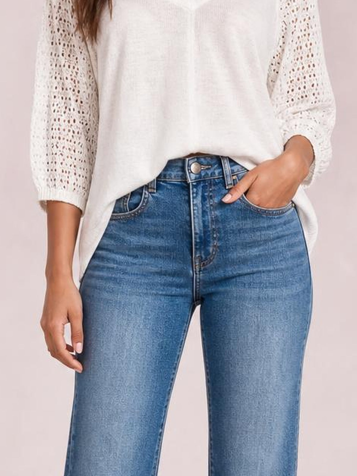 A model wears light blue high-rise bootcut jeans with a fitted silhouette, front pockets, belt loops, button closure, and subtle distressed denim texture.