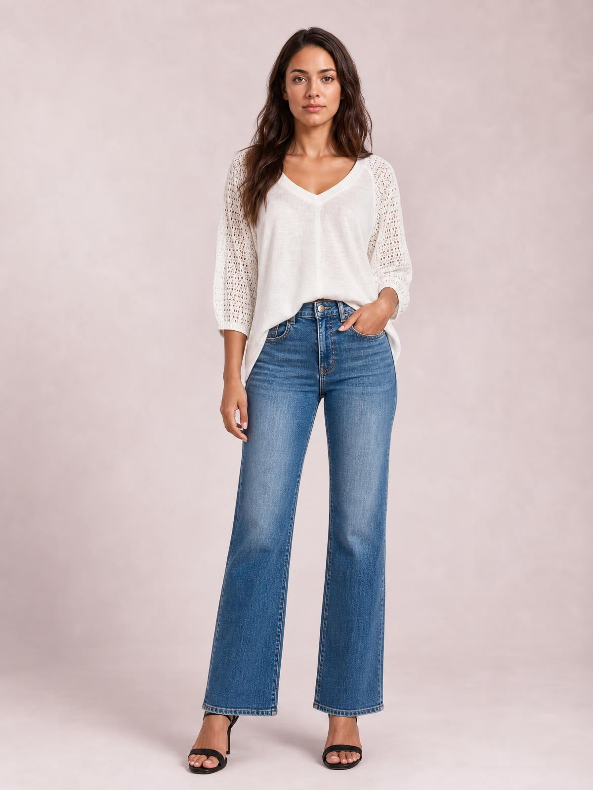 Model poses in blue high-rise bootcut jeans with front pockets, a button fly, fitted hips and thighs, and subtly flared legs.