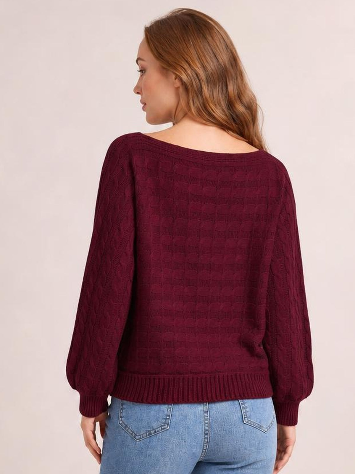 Model shown from the back wearing a burgundy cable-knit boat neck sweater with long sleeves, ribbed cuffs and hem, and a relaxed silhouette.