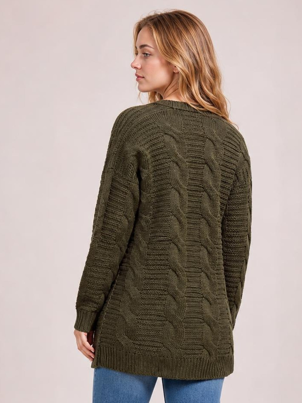 Model turned to show the back of an olive cable-knit open-front cardigan with long sleeves, a relaxed silhouette, ribbed trim, and textured braided stitching.