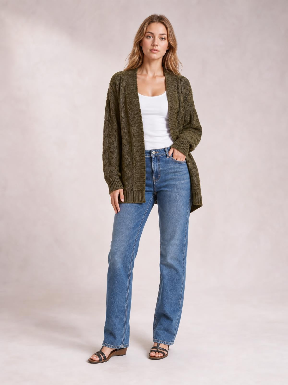 Model wears an olive-brown cable-knit open-front long-sleeve cardigan with a relaxed longline silhouette, ribbed edges, and textured vertical detailing.