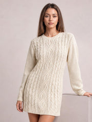 Model poses in a cream cable-knit sweater mini dress with long sleeves, a round neckline, ribbed cuffs and hem, and a relaxed straight silhouette.