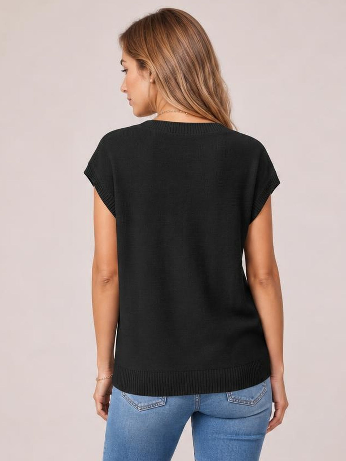 A model turns over her shoulder wearing a black cable-knit short-sleeve top with a relaxed silhouette and ribbed neckline, cuffs, and hem.
