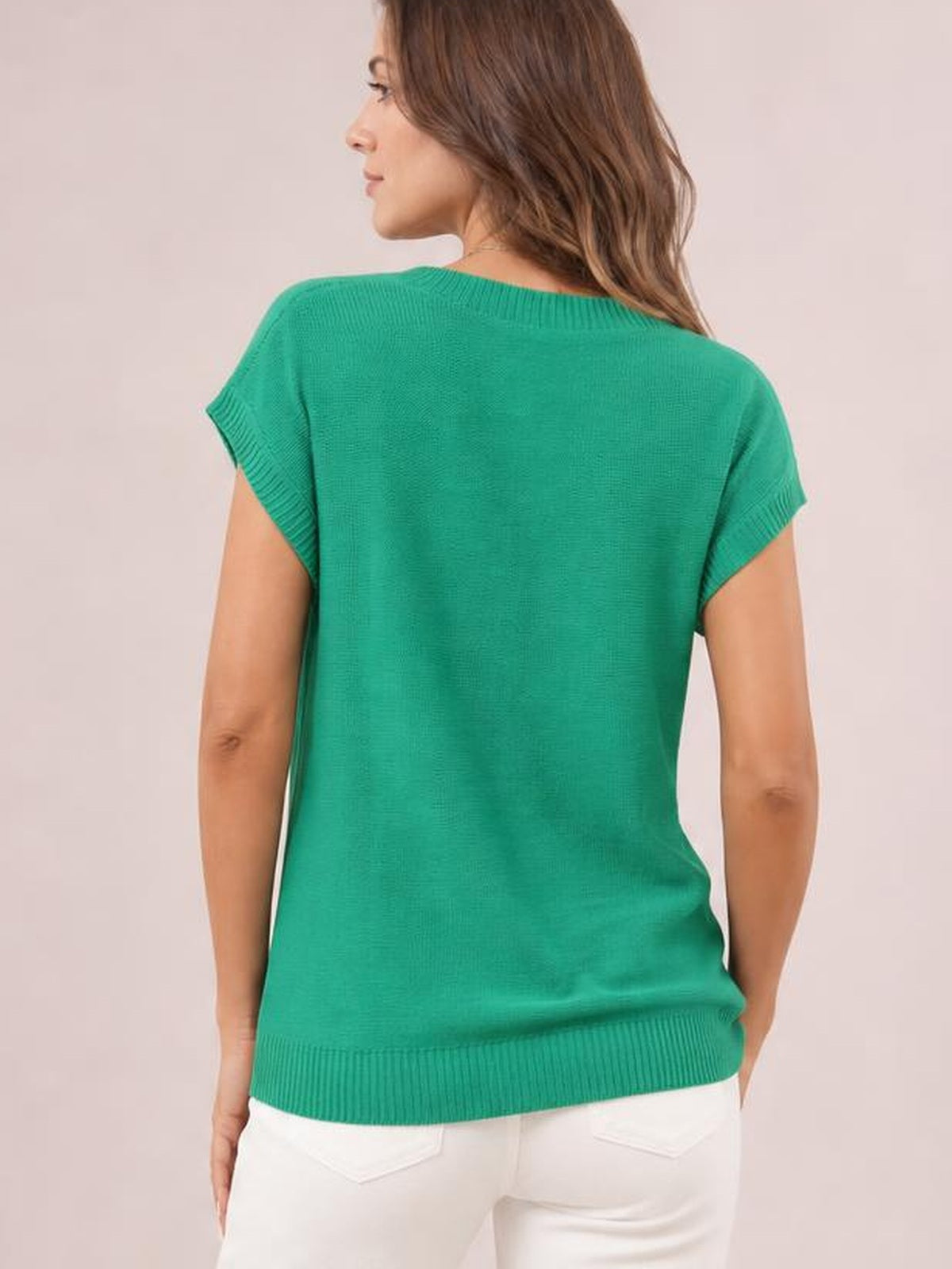 A model shown from behind wears a bright green short-sleeve knit top with ribbed cuffs and hem in a relaxed, straight silhouette.