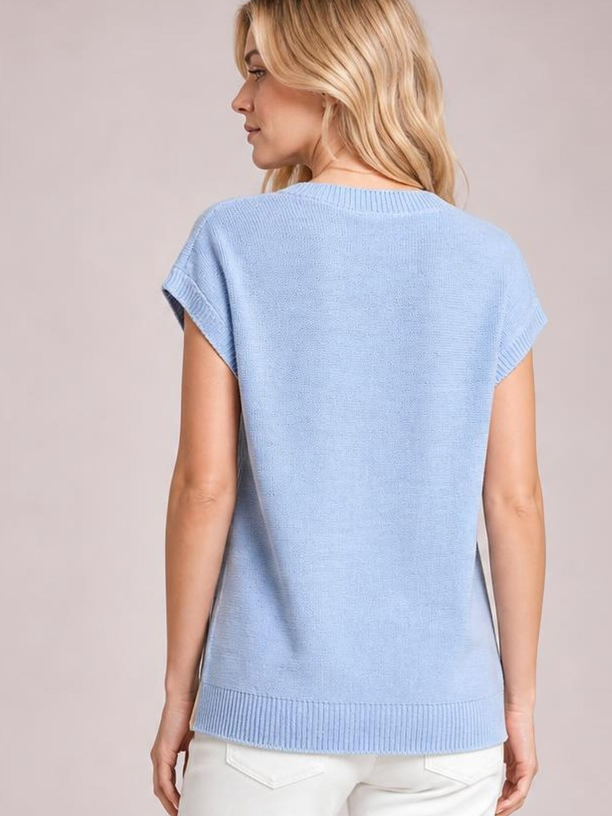 Model shown from the back in a pale blue cable-knit short sleeve top with a relaxed straight silhouette, ribbed neckline, rolled cuffs, and hem.