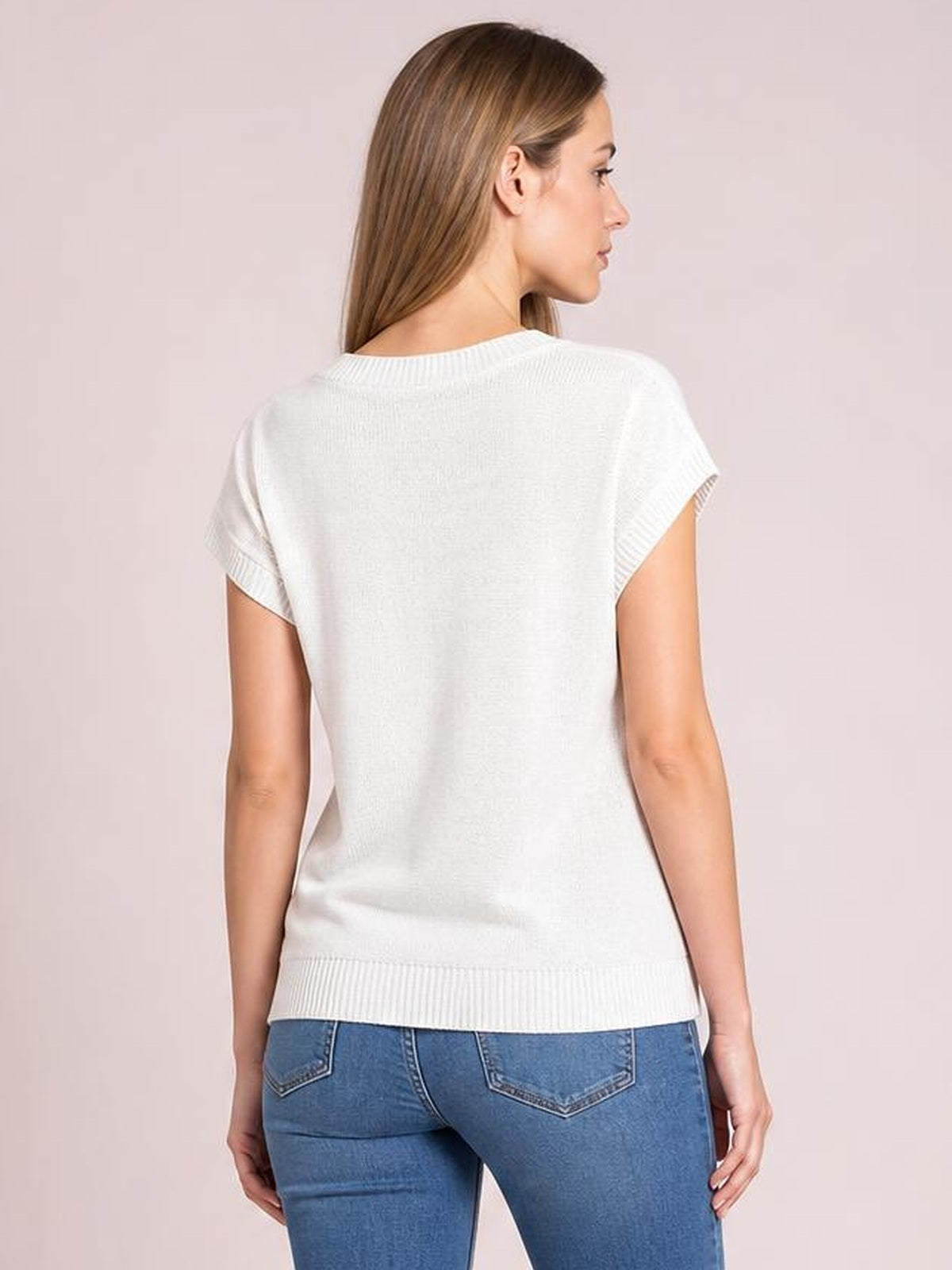 Model shown from behind wearing a white cable-knit short sleeve knit top with a relaxed silhouette, ribbed sleeve cuffs and hem, and blue jeans.