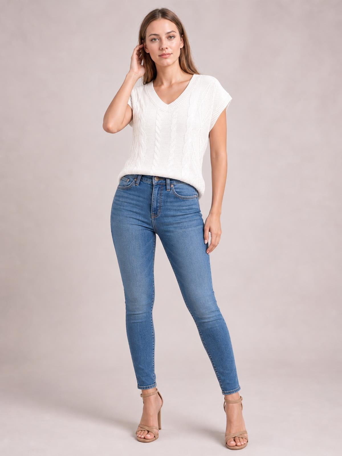 Model poses in a white cable-knit V-neck short sleeve top with a relaxed straight silhouette and ribbed neckline and sleeve edges.