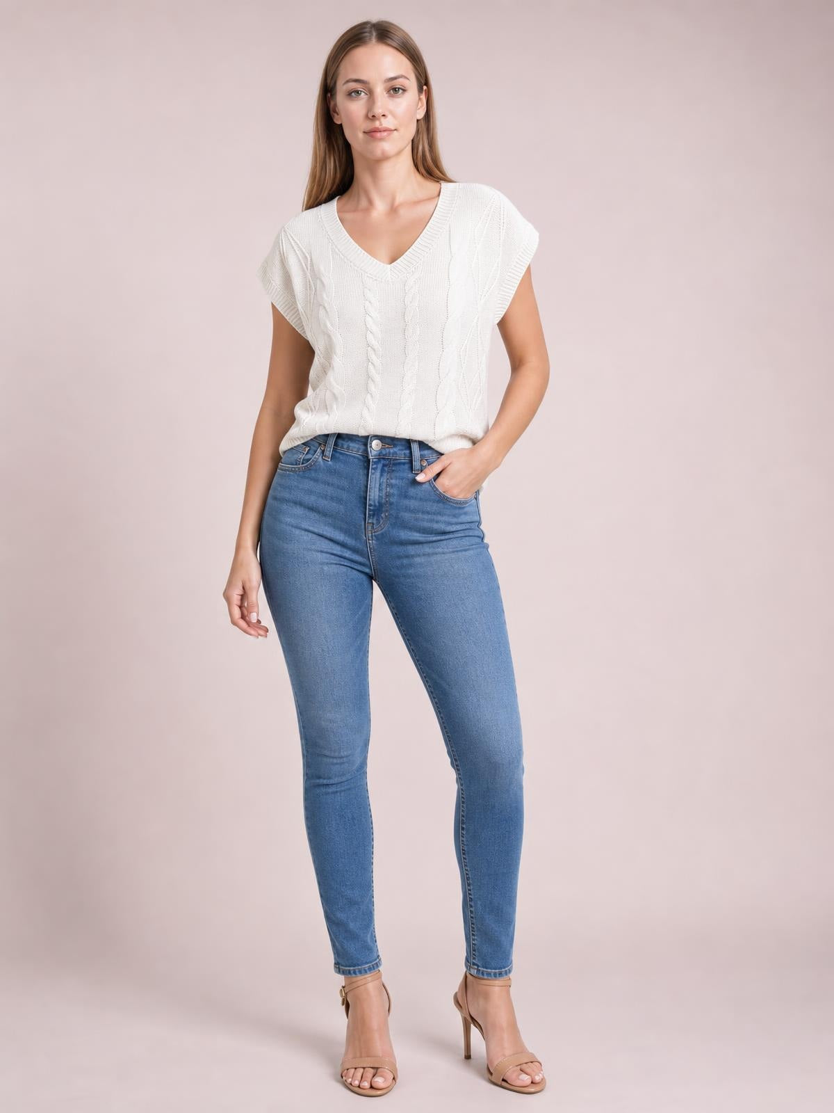 Model wears a white cable-knit V-neck short-sleeve top with a relaxed silhouette, standing with one hand in her jeans pocket.