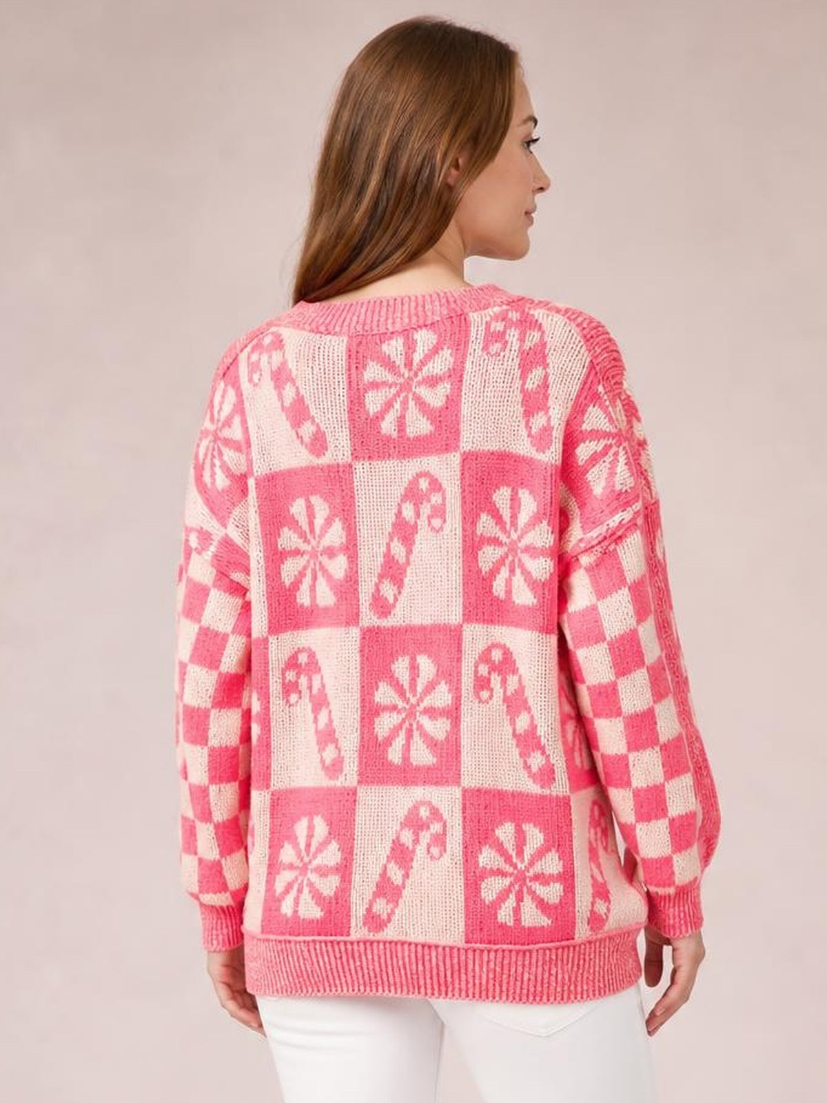 Model shown from the back wearing a pink and white round neck long sleeve sweater with a relaxed silhouette, ribbed cuffs and hem, and patchwork motifs.