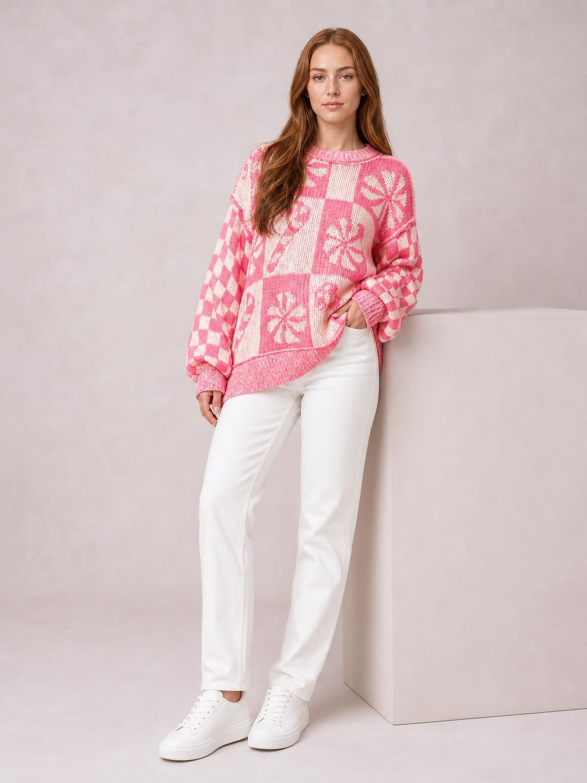 A model poses in a pink and white round neck long sleeve sweater with a relaxed silhouette, patchwork floral and checker pattern, and ribbed cuffs and hem.
