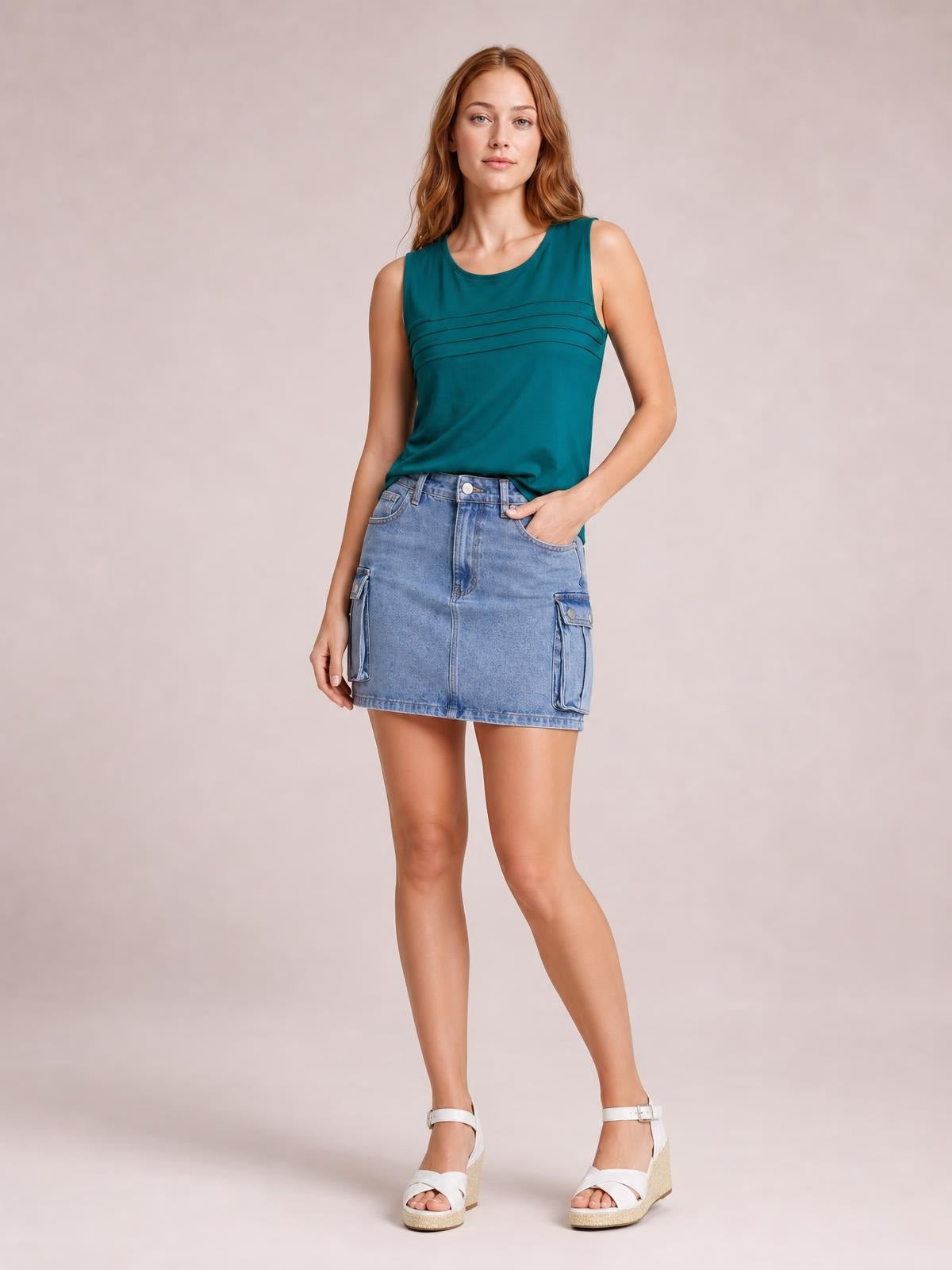 A model poses in a light blue Cargo Denim Skirt with a straight mini silhouette, front button closure, belt loops, seam details, and flap cargo pockets.