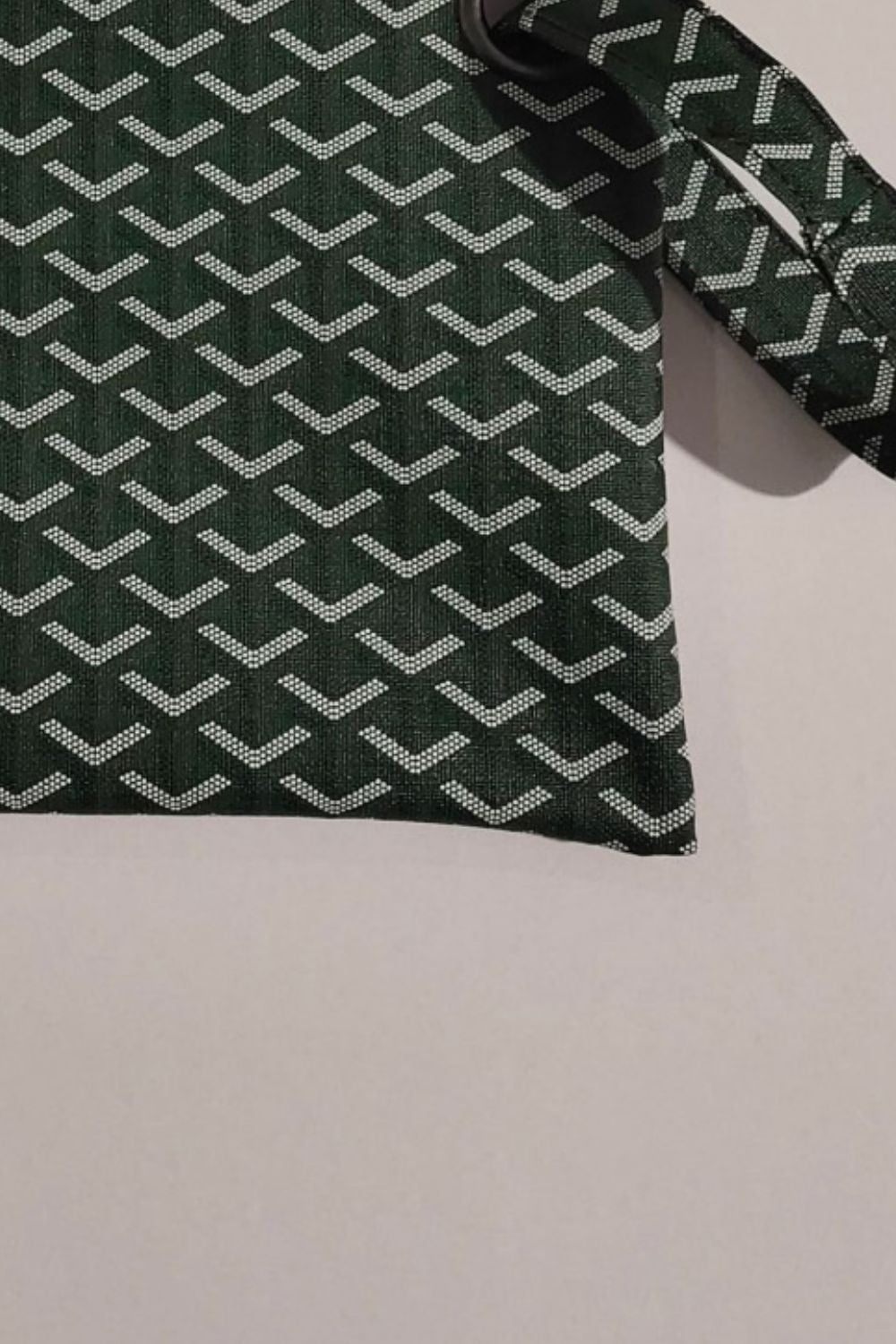 Dark green PU leather wristlet with a clean rectangular silhouette, repeating white chevron pattern, and a visible wrist strap in a flat-lay view.