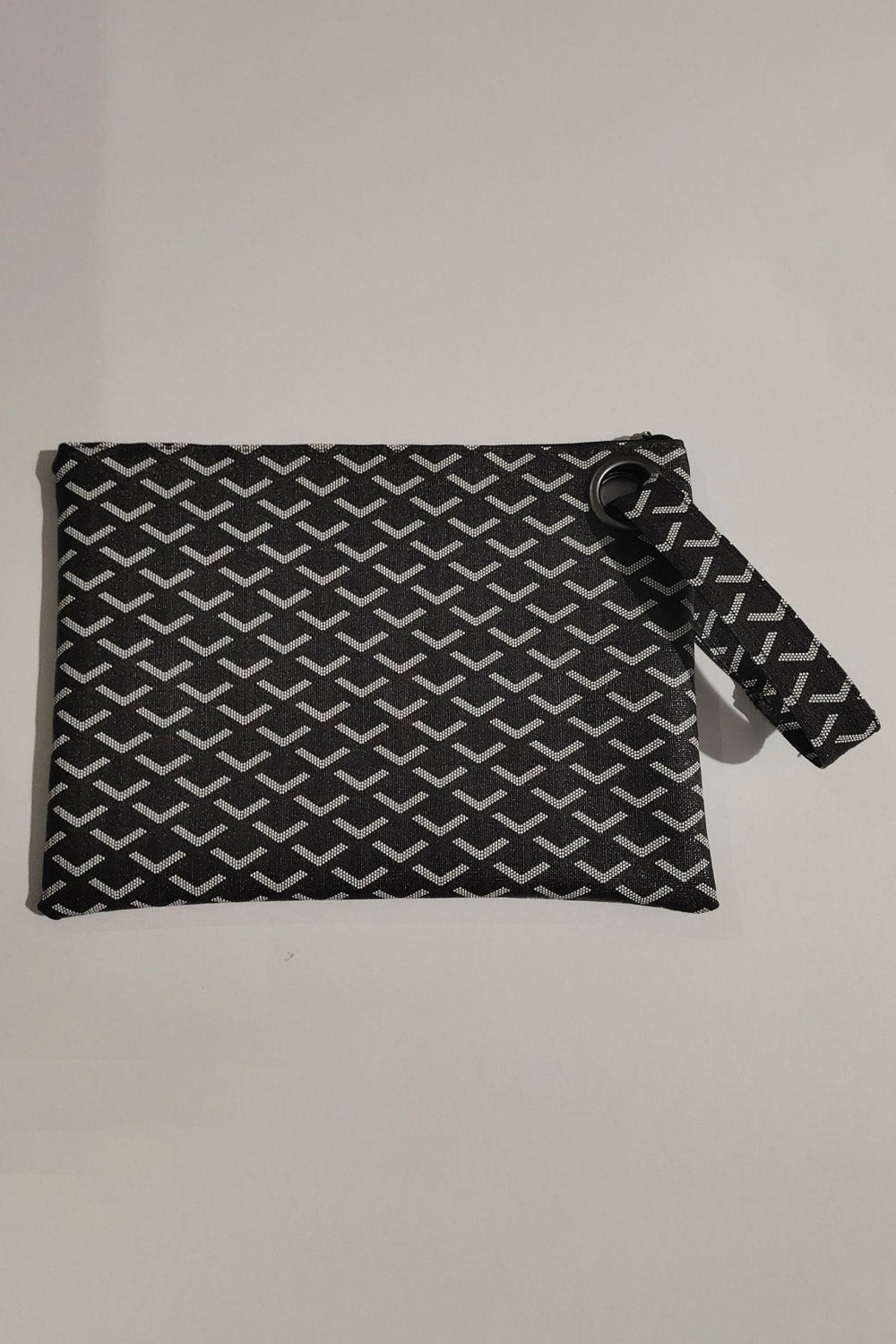 Black and white geometric-patterned PU leather wristlet with a clean rectangular silhouette, top zipper, and detachable wrist strap.