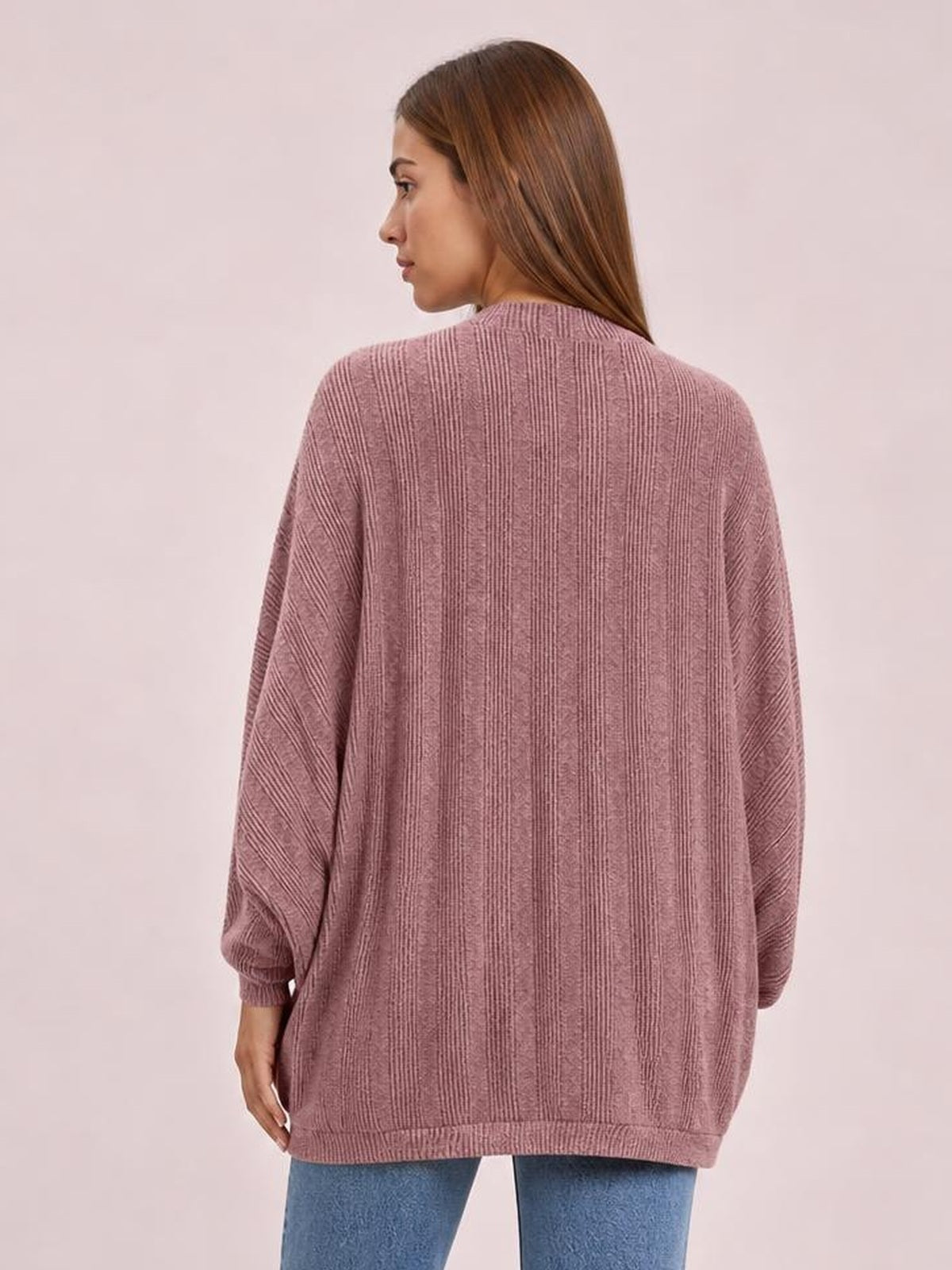 Model poses turned to the side in a mauve knit open-front cardigan with a relaxed oversized silhouette, long sleeves, ribbed cuffs, hem, and vertical texture.