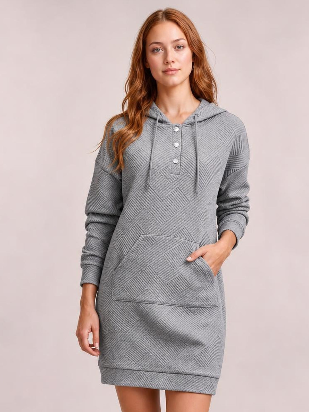 Model wears a gray textured hooded sweatshirt dress with long sleeves, drawstring hood, button placket, kangaroo pocket, and relaxed straight silhouette.