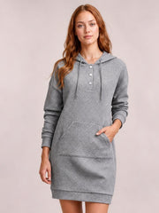 Model wears a gray textured hooded sweatshirt dress with long sleeves, drawstring hood, button placket, kangaroo pocket, and relaxed straight silhouette.