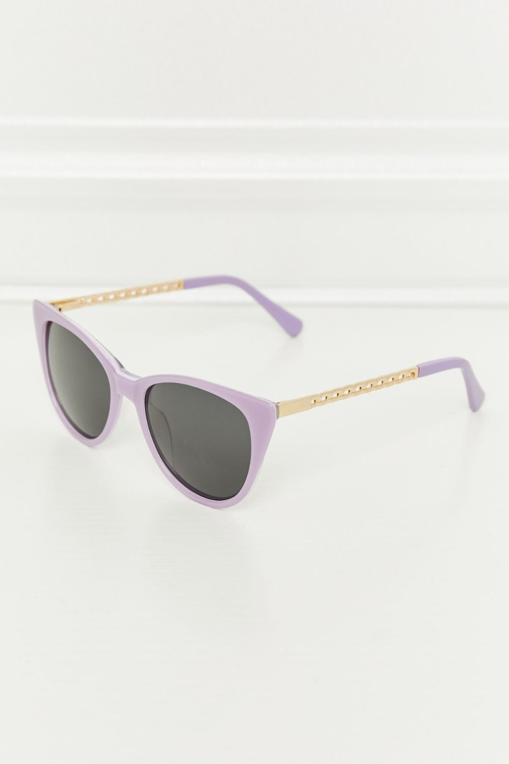 Lavender cat-eye acetate sunglasses feature softly upswept frames, dark lenses, and gold-tone metal temples with lavender acetate tips.