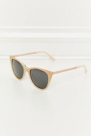 Tan acetate cat-eye sunglasses feature a softly upswept silhouette, dark lenses, and slender temples with refined metal and acetate detailing.