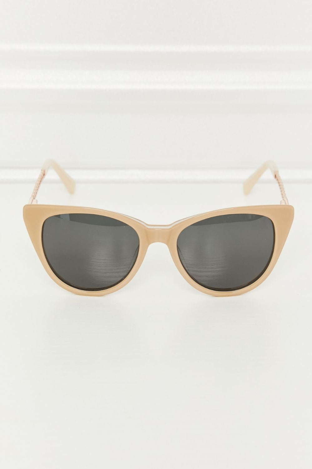 Tan acetate cat-eye sunglasses feature a softly upswept silhouette, dark TAC polarized lenses, and slim metal-and-acetate temples.
