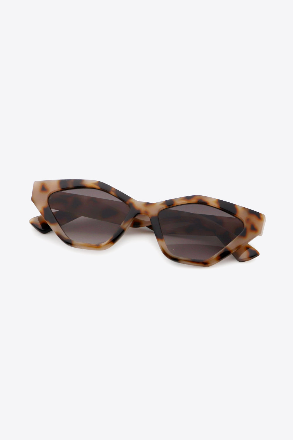 Tortoiseshell cat-eye sunglasses feature angular dark lenses, sculpted polycarbonate frames, and lifted outer corners for a sharp, fashion-forward silhouette.