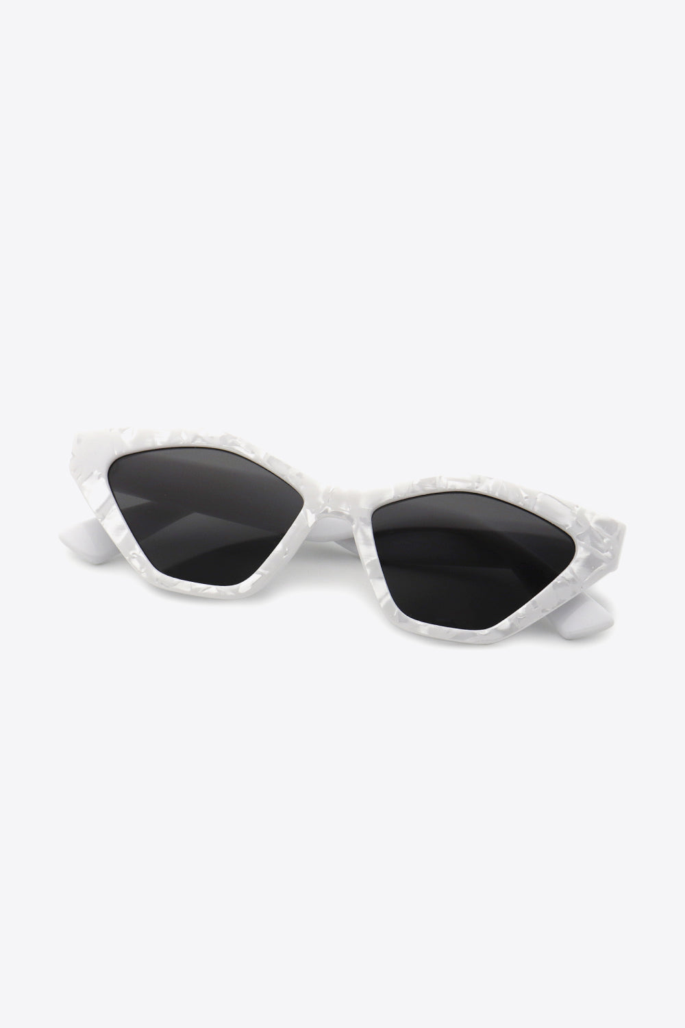 White polycarbonate cat-eye sunglasses feature angular black lenses, lifted outer corners, and sculpted translucent frames with folded temples.