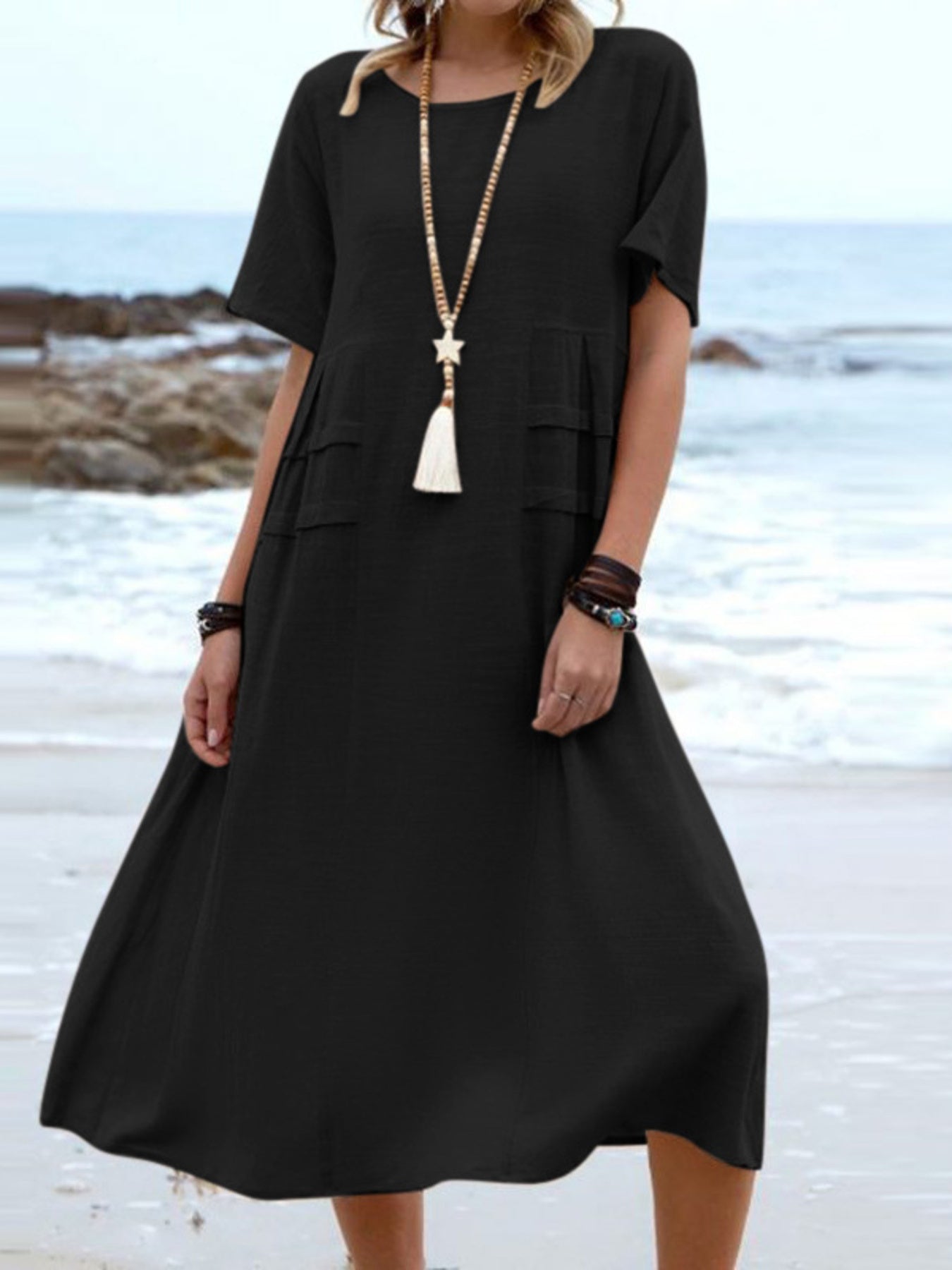 Plus size loose midi dress with short sleeves and pockets shown in cream and black by the beach