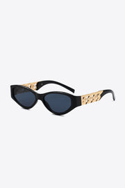 Black cat-eye sunglasses feature an upswept silhouette, dark lenses, and polished gold chain-detail temples shown in a three-quarter view.
