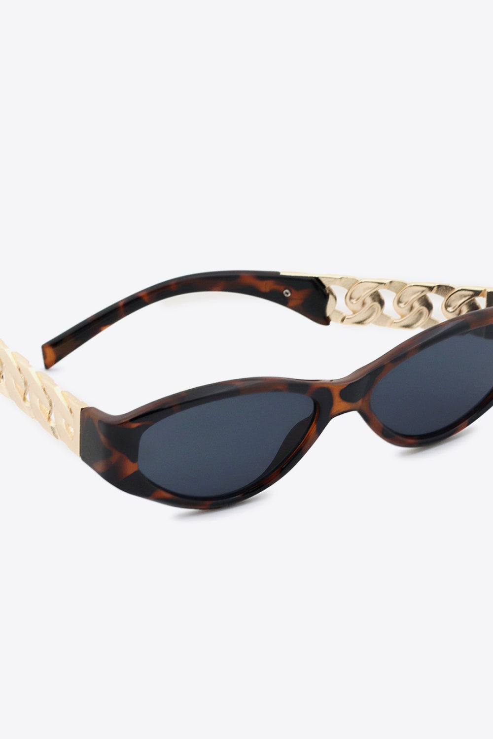 Tortoiseshell cat-eye sunglasses feature dark lenses, an upswept silhouette, and polished gold chain-detail temples with a structured polycarbonate frame.