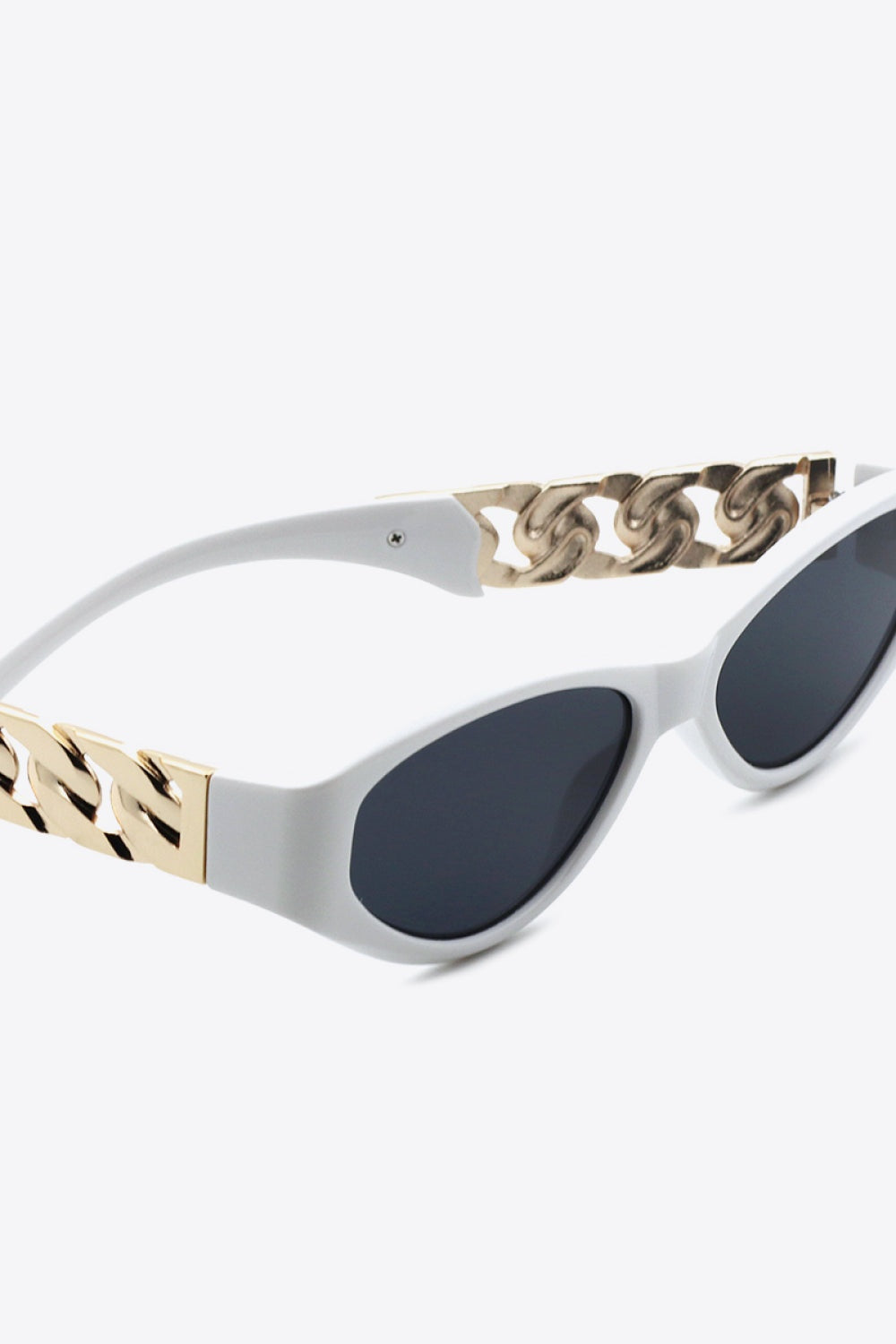 White cat-eye sunglasses feature dark lenses, an upswept silhouette, and polished gold chain detail along the temples.