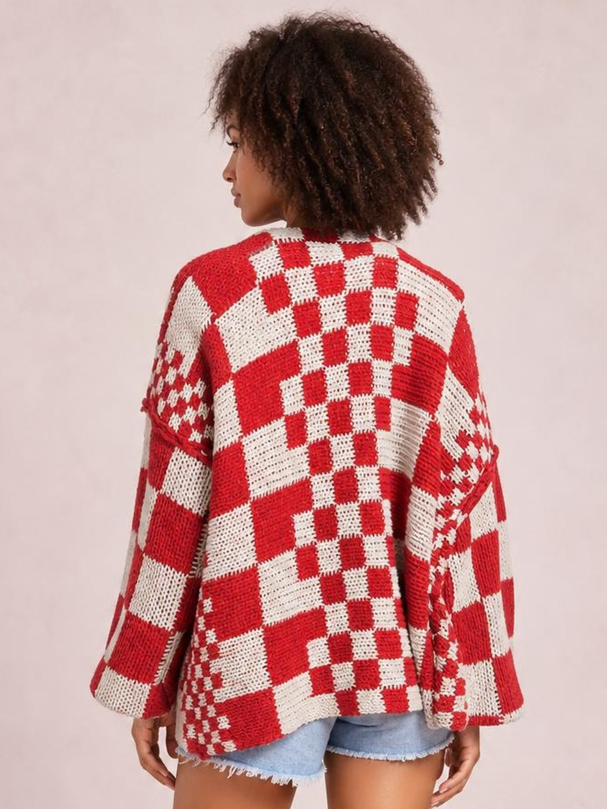 Model shown from behind wearing a red-and-white checkered open-front long-sleeve cardigan with a relaxed, oversized silhouette and textured knit construction.