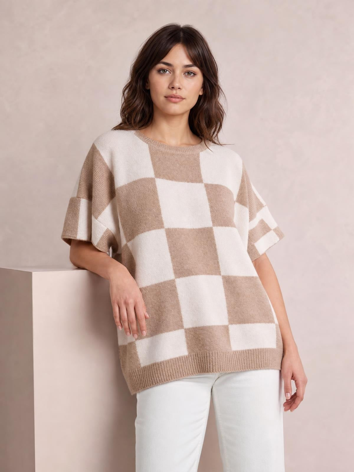 Model wearing a beige and cream checkered loose sweater with a drop shoulder, half sleeves, ribbed crew neckline and hem, and relaxed long silhouette.